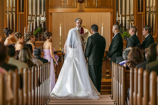 bride-and-groom-standing-at-altar-during-wedding-ceremony-picture-id554372721